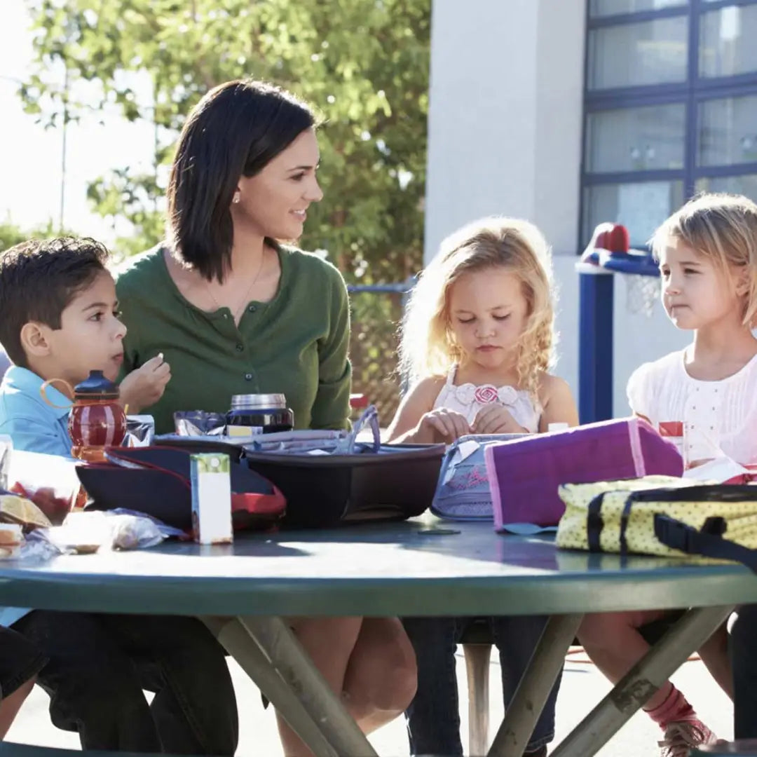 Woman with three children sitting at a picnic table outdoors