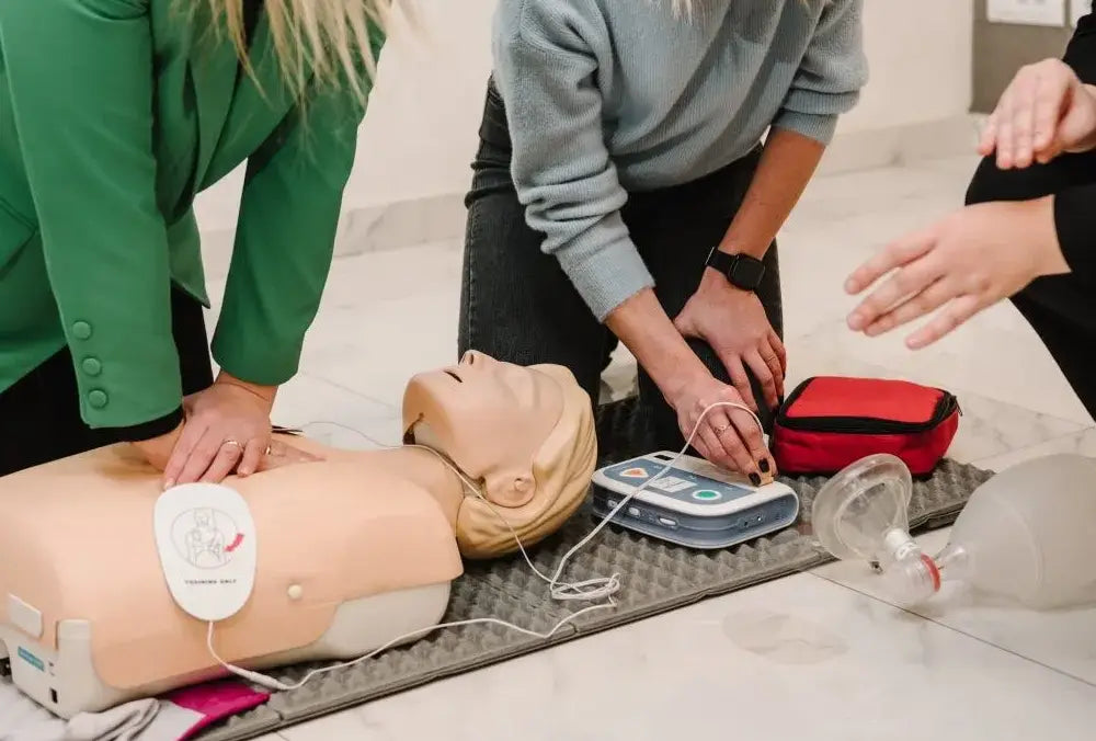 CPR training simulation with a mannequin and instructor demonstrating techniques.