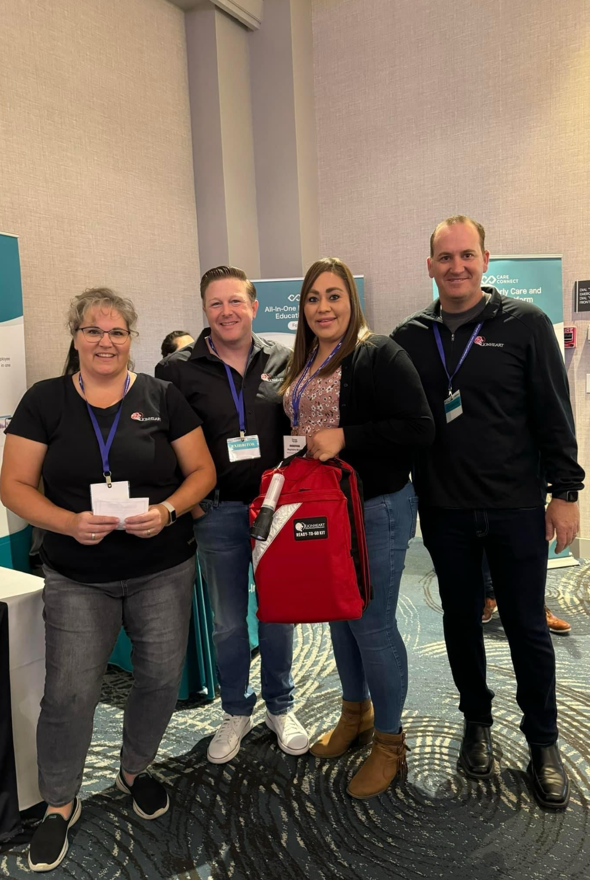 Four people standing together at an event, with one person holding a red bag.