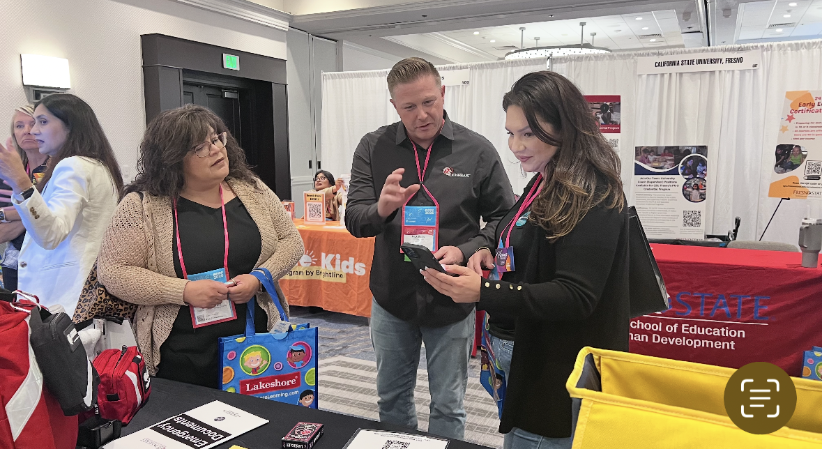 People at a trade show or event with booths and displays.