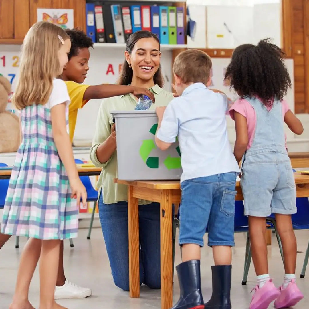 Teacher and students in a classroom with a recycling bin