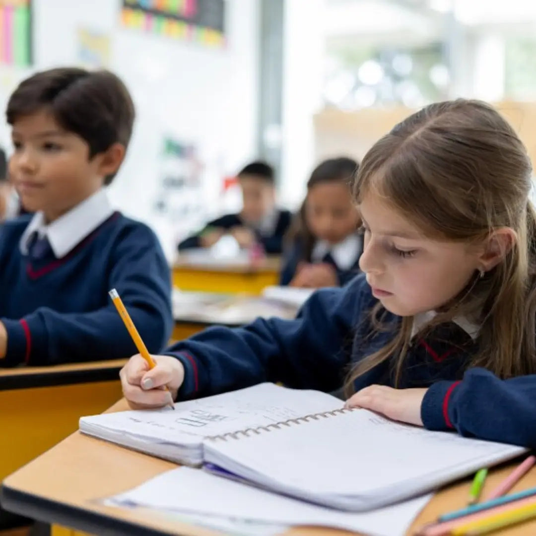 Children in a classroom setting with one child writing in a notebook.