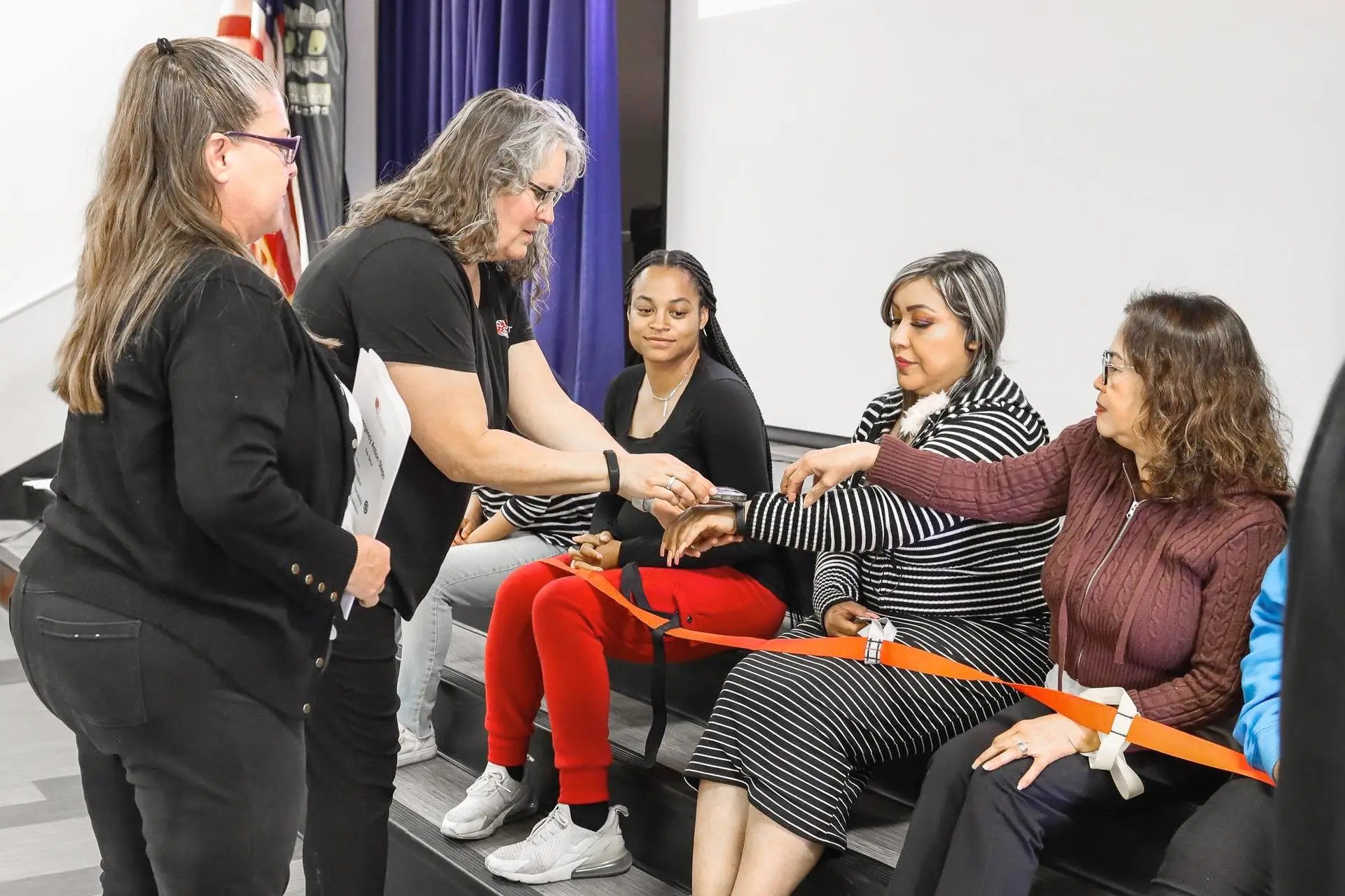 Group of women sitting on a couch with one woman standing and interacting with them.
