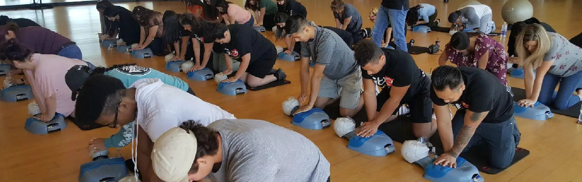 Group of people participating in a CPR training session on blue manikins.